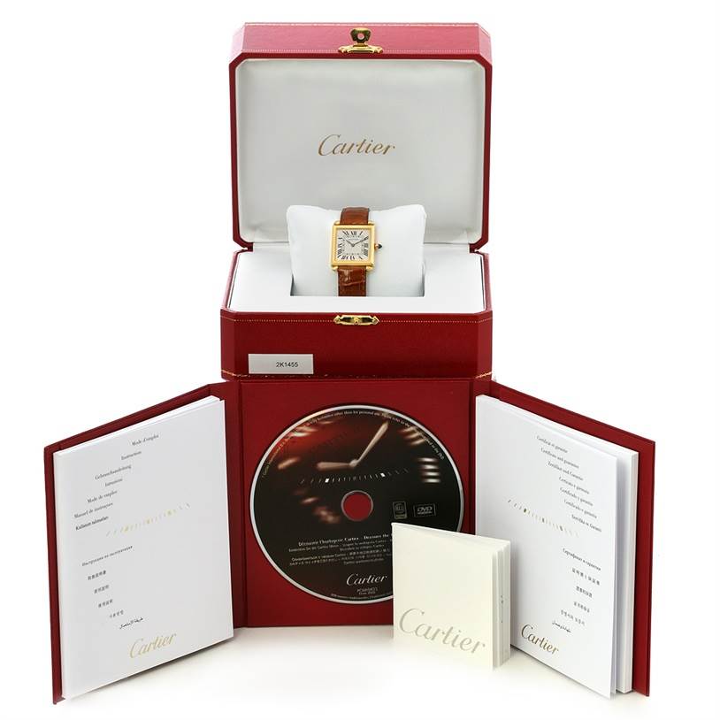 The image shows a Cartier Tank Obus W1512256 Yellow Gold Silver Dial W1512256 Yellow Gold Silver Dial watch with its packaging, including a box, manual, and CD, from a front angle.