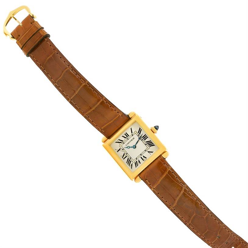 The Cartier Tank Obus W1512256 Yellow Gold Silver Dial W1512256 Yellow Gold Silver Dial watch is shown from a top-down angle, displaying its square face, brown leather strap, and gold casing.