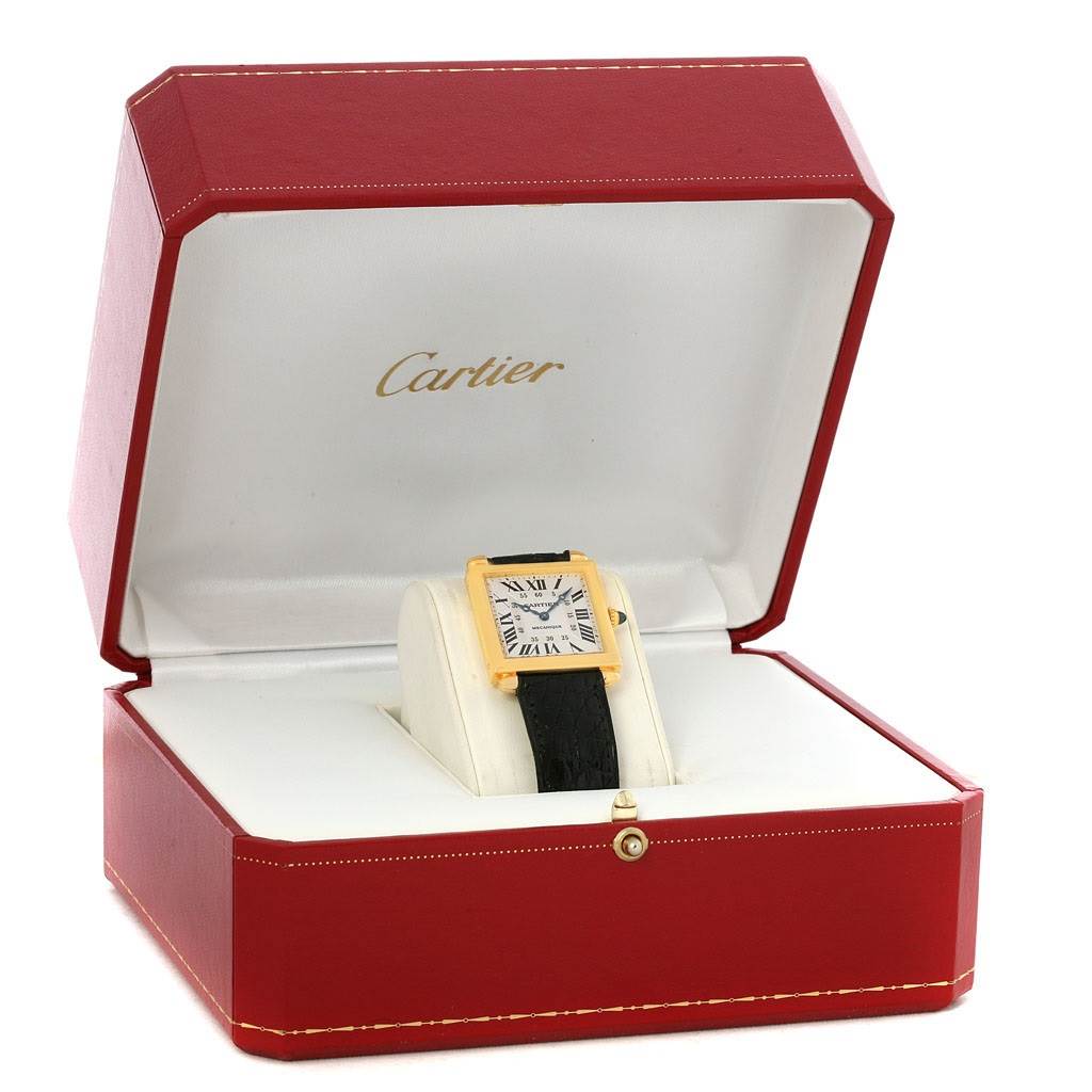 The Tank Obus watch by Cartier is shown in its open red case, displaying the watch face and strap.