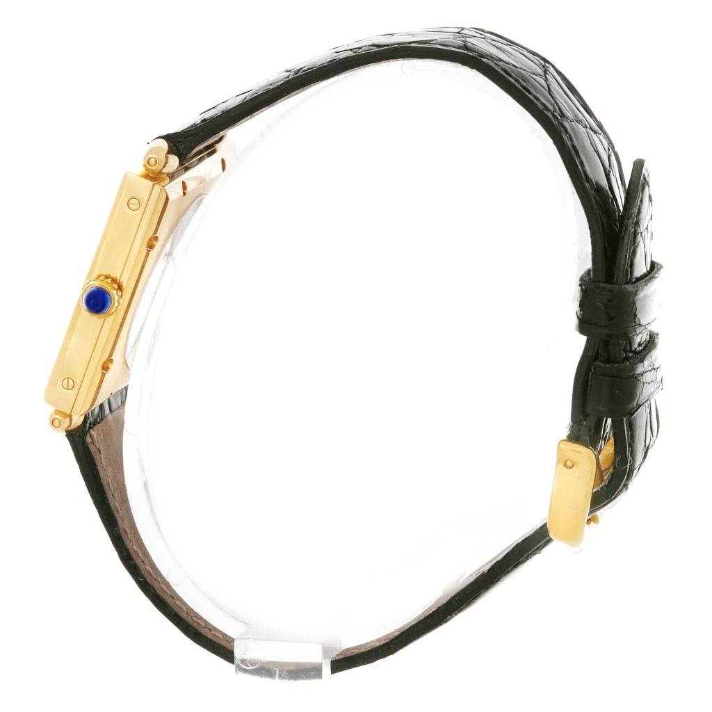 The image shows the side view of a Cartier Tank Obus W1527551 Men's Yellow Gold Silver Dial W1527551 Men's Yellow Gold Silver Dial watch, highlighting its gold case, blue cabochon crown, and black leather strap.