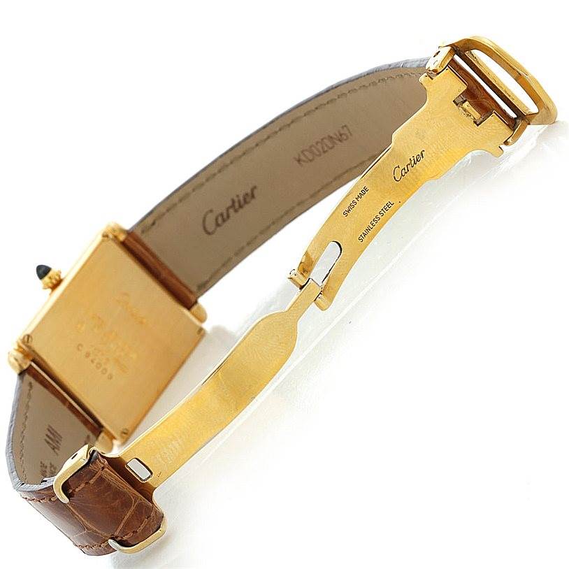 The image shows the back view of a Cartier Tank Obus Men's Yellow Gold Silver Dial Men's Yellow Gold Silver Dial watch, highlighting the clasp and part of the leather strap.