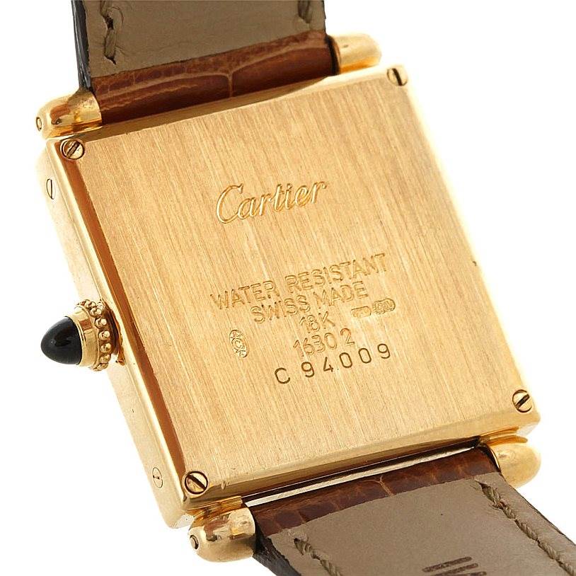 This image shows the back and side of the Cartier Tank Obus Men's Yellow Gold Silver Dial Men's Yellow Gold Silver Dial watch, highlighting the gold case, engravings, and leather strap.