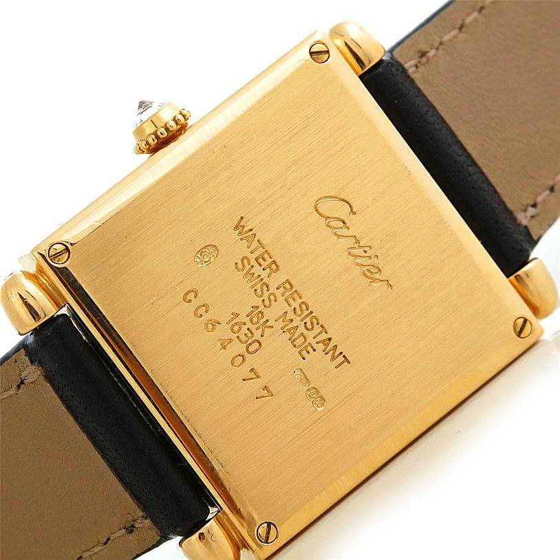 The image shows the back case of a Cartier Tank Obus W1512256 Men's Yellow Gold Silver Dial W1512256 Men's Yellow Gold Silver Dial watch, featuring inscriptions and part of the leather strap.