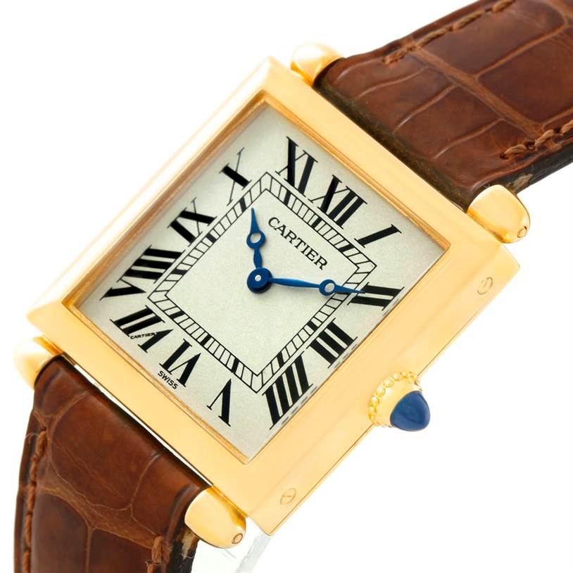 The Tank Obus by Cartier is shown at an angled close-up, highlighting its square gold case, Roman numeral dial, and brown leather strap.