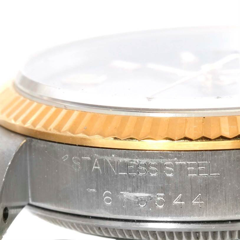 This close-up angle of the Rolex Oyster Perpetual 14233 Men's Steel and Gold (two tone) Grey Dial 14233 Men's Steel and Gold (two tone) Grey Dial watch shows the side of the case with "STAINLESS STEEL" and parts of the bezel and crystal.