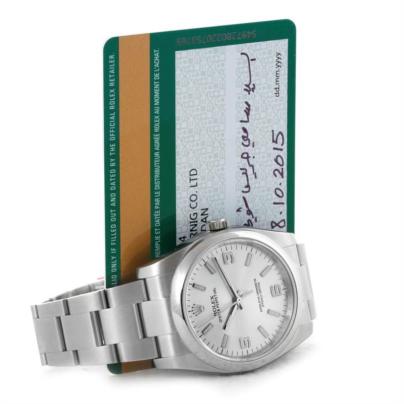 The image shows a Rolex Oyster Perpetual 116000 Men's Stainless Steel Silver Dial 116000 Men's Stainless Steel Silver Dial watch laid down, with its face, band, and crown visible, placed in front of an official documentation card.