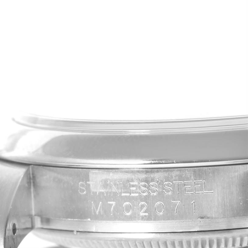 The image shows a side view of the casing of a Rolex Oyster Perpetual 116000 Men's Stainless Steel Black Dial 116000 Men's Stainless Steel Black Dial watch, highlighting the stainless steel material and serial number.