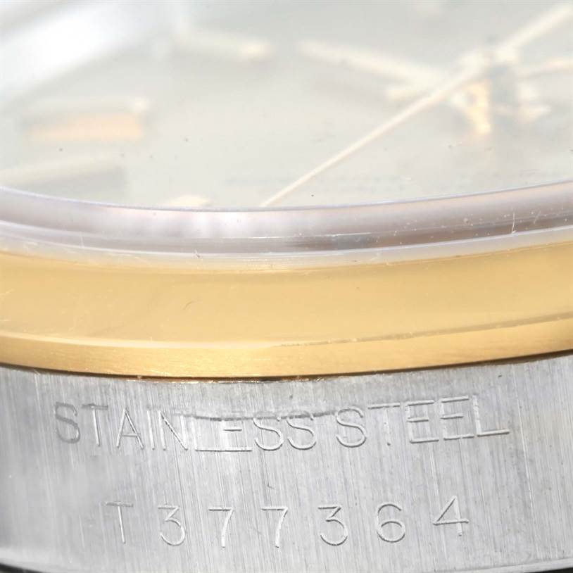 This close-up photo shows the side of the Rolex Oyster Perpetual 14203 Men
s Steel and Gold (two tone) Champagne Dial 14203 Men
s Steel and Gold (two tone) Champagne Dial watch, highlighting its stainless steel case and engraved serial number.