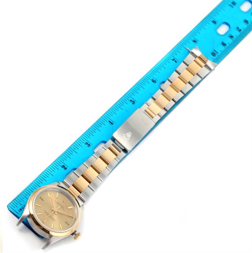 The image shows a top-down view of a Rolex Oyster Perpetual 14203 Men
s Steel and Gold (two tone) Champagne Dial 14203 Men
s Steel and Gold (two tone) Champagne Dial watch with a two-tone bracelet beside a blue ruler.