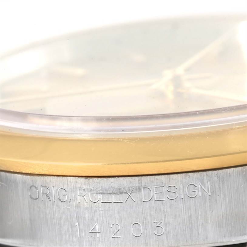 This image shows a close-up of the bezel, crystal, and part of the side case of a Rolex Oyster Perpetual 14203 Men
s Steel and Gold (two tone) Champagne Dial 14203 Men
s Steel and Gold (two tone) Champagne Dial watch, including engraved text.
