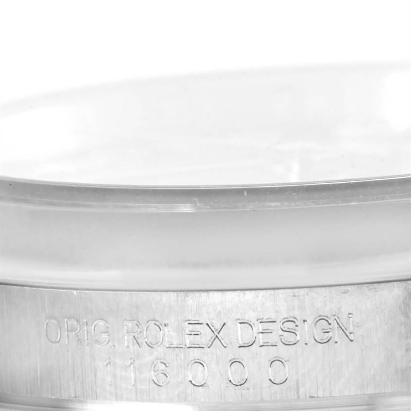 The image shows a partial side view of a Rolex Oyster Perpetual 116000 Men's Stainless Steel Black Dial 116000 Men's Stainless Steel Black Dial model, focusing on the engraved text on the watch casing.