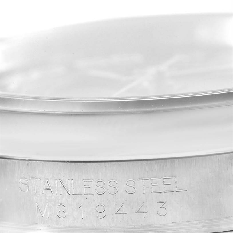 This image shows a close-up of the side case of a Rolex Oyster Perpetual 116000 Men's Stainless Steel Black Dial 116000 Men's Stainless Steel Black Dial watch, highlighting the "Stainless Steel" engraving and model number M619443.