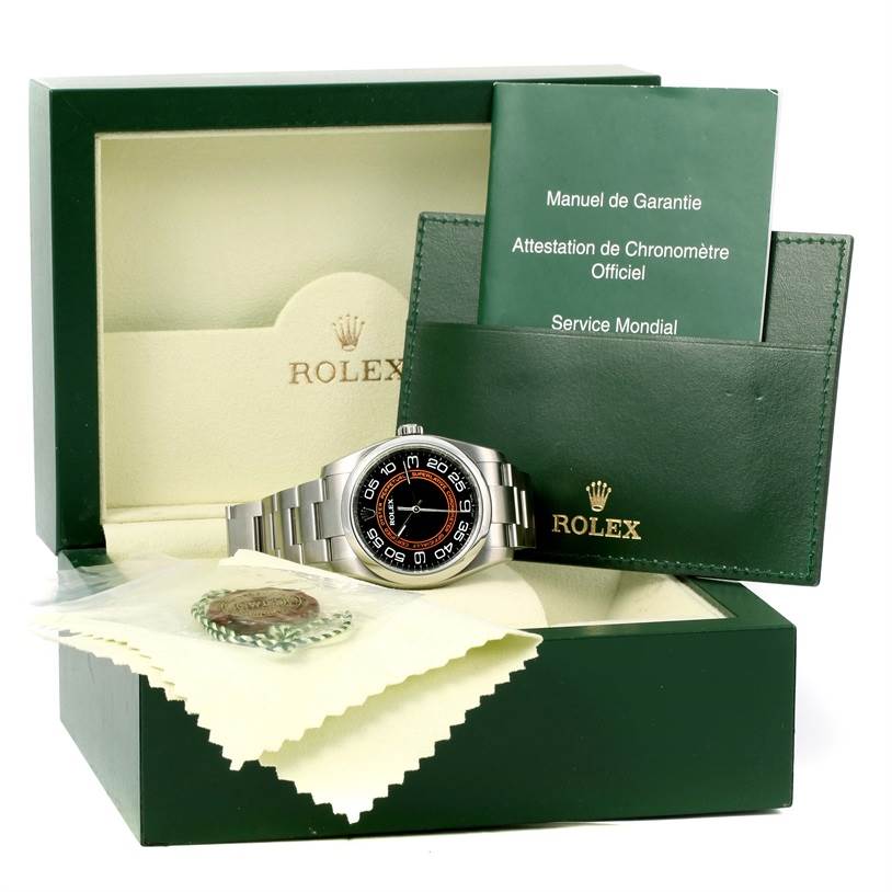 This image shows a Rolex Oyster Perpetual 116000 Men's Stainless Steel Black Dial 116000 Men's Stainless Steel Black Dial watch placed in its open box with accompanying manuals, pouch, and a tag.