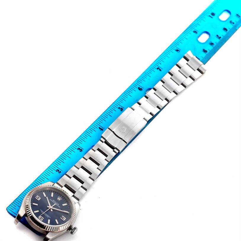 The image shows an overhead view of a Rolex Oyster Perpetual 116034 Men
s Stainless Steel Blue Dial 116034 Men
s Stainless Steel Blue Dial watch, including its face, bezel, crown, and full metal bracelet alongside a ruler.