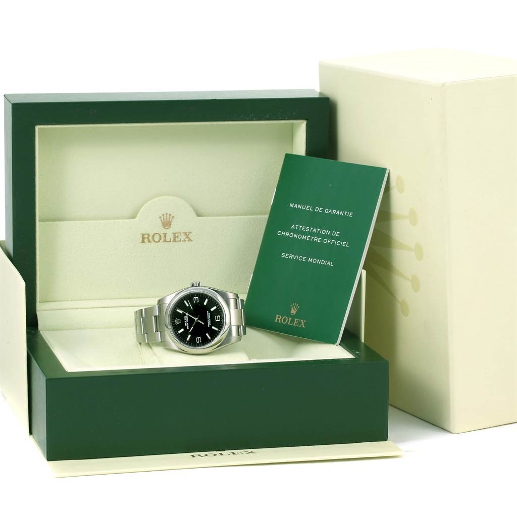 The Oyster Perpetual Rolex watch is shown inside its open box, accompanied by documentation and the packaging.