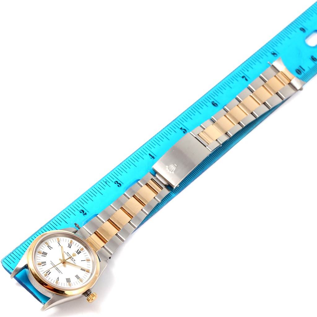 The image shows a Rolex Oyster Perpetual 14203 Men
s Steel and Gold (two tone) White Dial 14203 Men
s Steel and Gold (two tone) White Dial watch laid flat next to a blue ruler, with a focus on the bracelet and clasp.