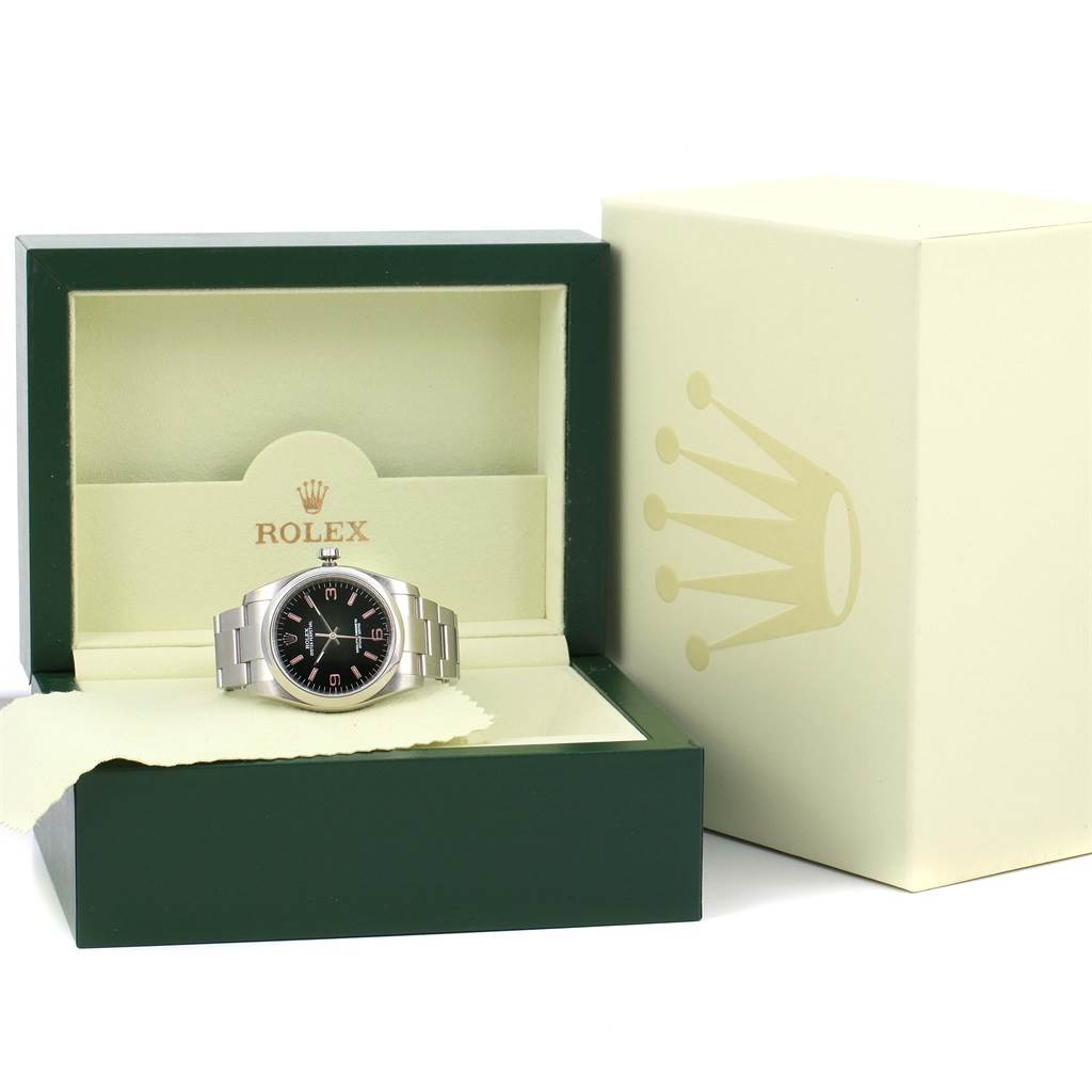 The Rolex Oyster Perpetual 116000 Men's Stainless Steel Black Dial 116000 Men's Stainless Steel Black Dial watch is shown front-facing in its open box with the outer box visible beside it.
