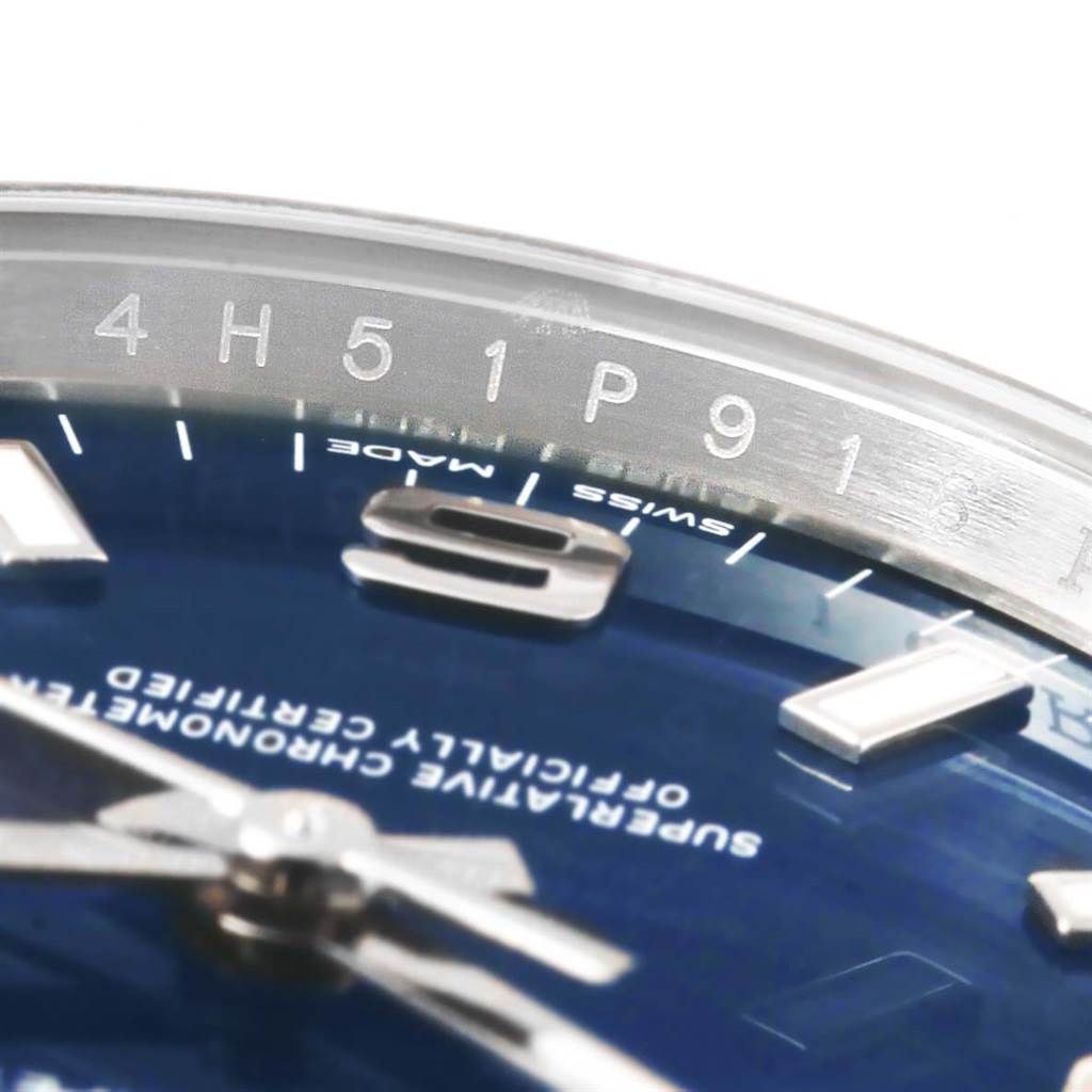 This close-up image shows part of the dial and numerals on a Rolex Oyster Perpetual 114200 Men's Stainless Steel Blue Dial 114200 Men's Stainless Steel Blue Dial watch, including some engraved details on the chapter ring.