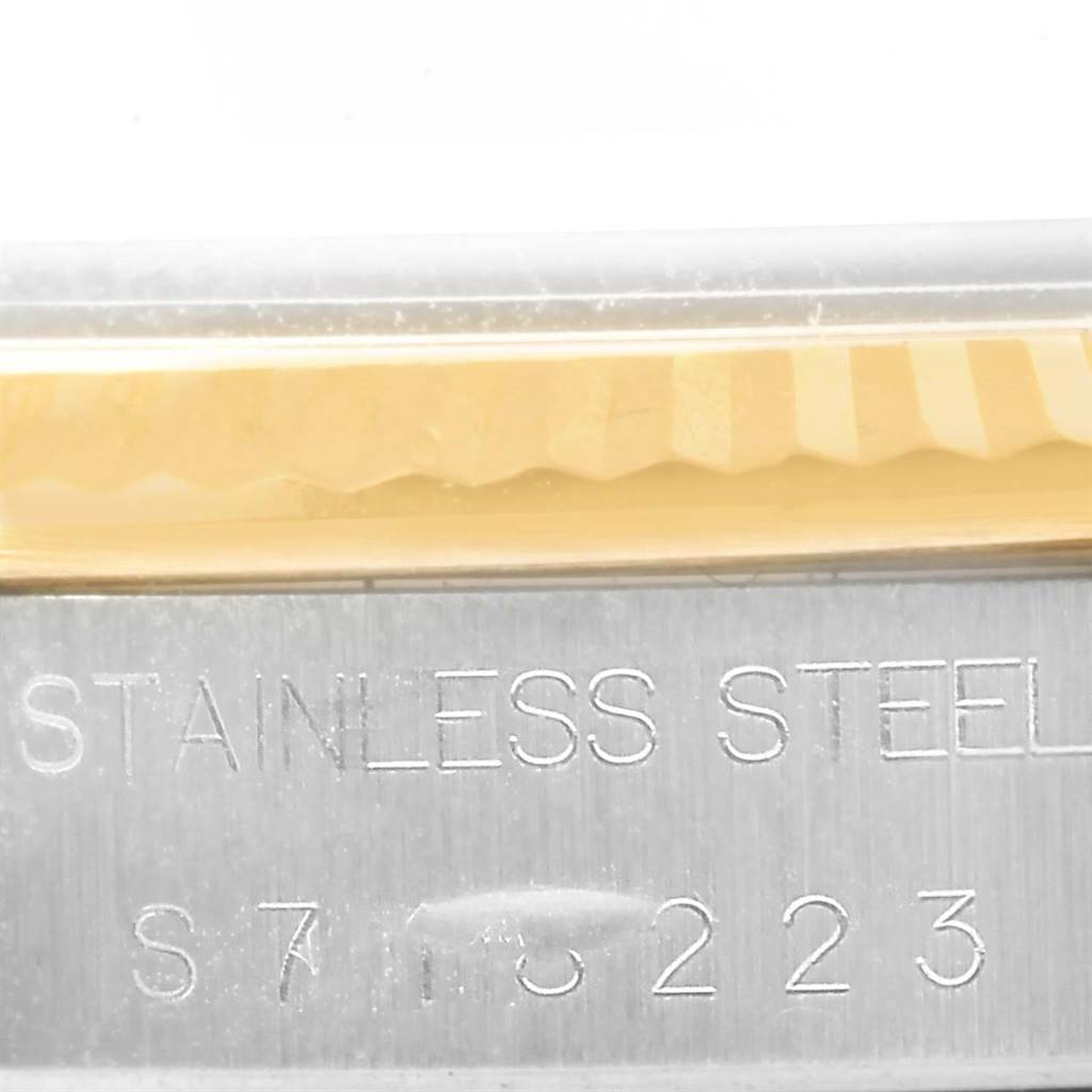 This image shows a close-up of the stainless steel part of a Rolex Oyster Perpetual 14233 Men's Steel and Gold (two tone) Champagne Dial 14233 Men's Steel and Gold (two tone) Champagne Dial watch with some engraving.