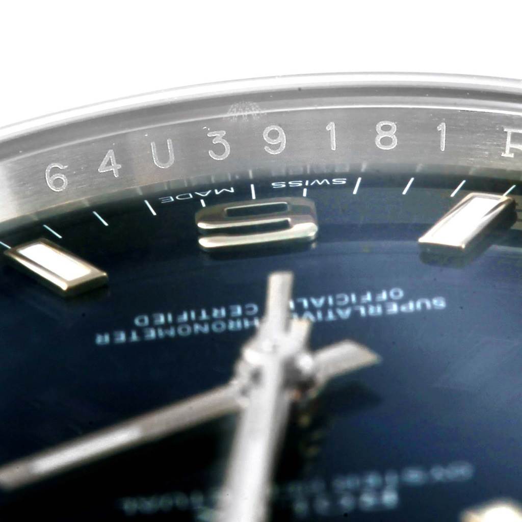 The image shows a close-up of the dial, indices, and part of the bezel of a Rolex Oyster Perpetual 114200 Men's Stainless Steel Blue Dial 114200 Men's Stainless Steel Blue Dial watch.