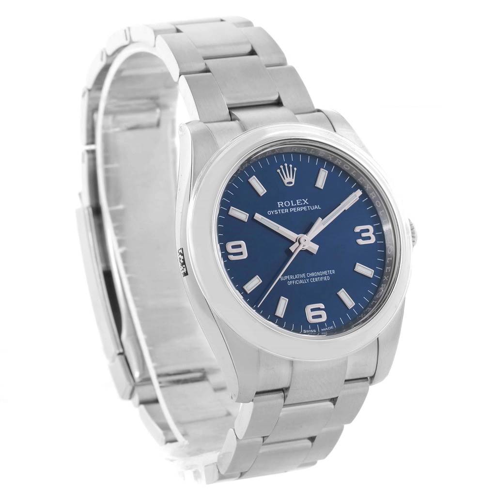 The image shows a Rolex Oyster Perpetual 114200 Stainless Steel Blue Dial 114200 Stainless Steel Blue Dial watch from a three-quarter angle, displaying the face, crown, and bracelet.