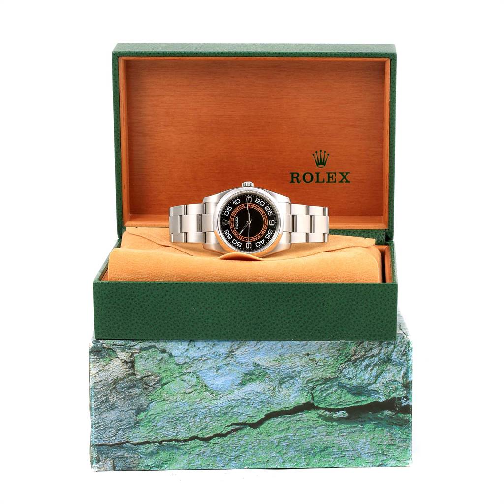 The Oyster Perpetual model by Rolex is shown from the front, placed inside an open green and orange Rolex box.