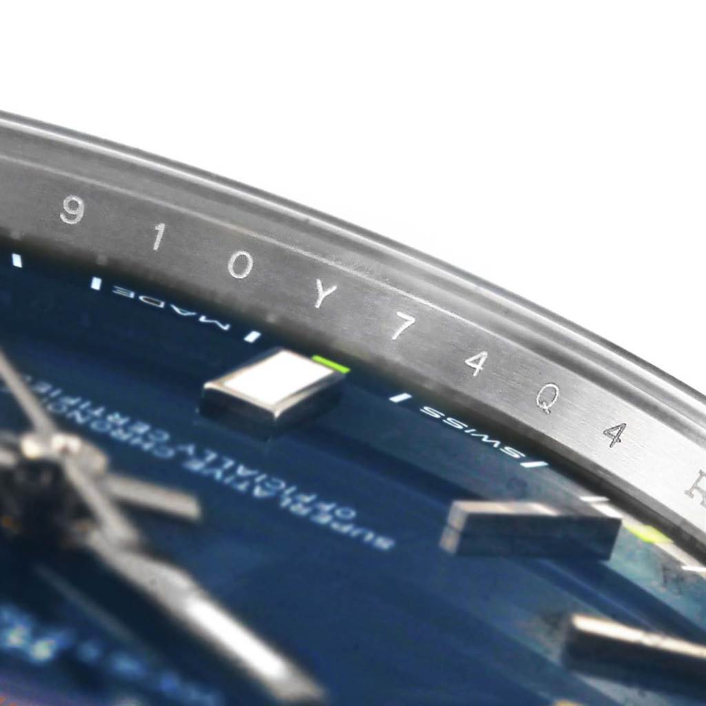 The image shows a close-up angle focusing on the bezel and partial dial of a Rolex Oyster Perpetual 114300 Men's Stainless Steel Blue Dial 114300 Men's Stainless Steel Blue Dial watch.