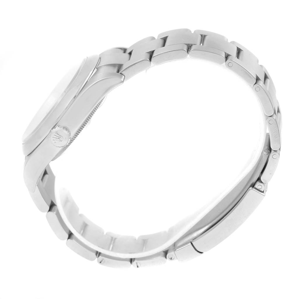 The image shows a side angle of a Rolex Oyster Perpetual 116000 Men's Stainless Steel Champagne Dial 116000 Men's Stainless Steel Champagne Dial watch highlighting its stainless steel case and bracelet.