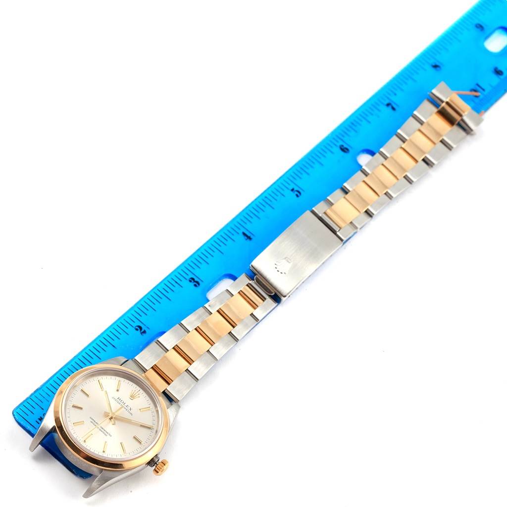 The Rolex Oyster Perpetual 14203 Men
s Steel and Gold (two tone) Silver Dial 14203 Men
s Steel and Gold (two tone) Silver Dial watch is shown from a top-down angle, displaying the face, the bezel, and the bracelet.