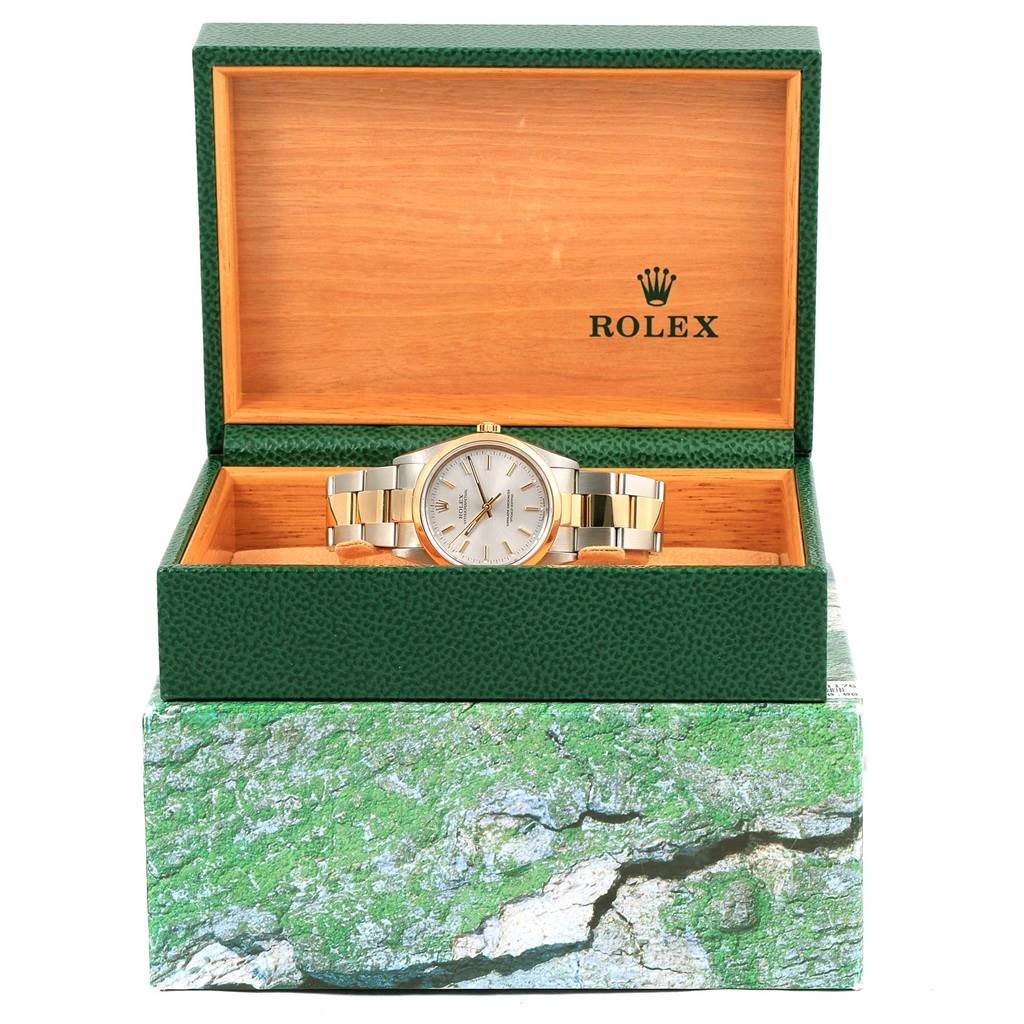 The Rolex Oyster Perpetual 14203 Men
s Steel and Gold (two tone) Silver Dial 14203 Men
s Steel and Gold (two tone) Silver Dial watch is shown from the front angle, displayed in an open green and wooden box.
