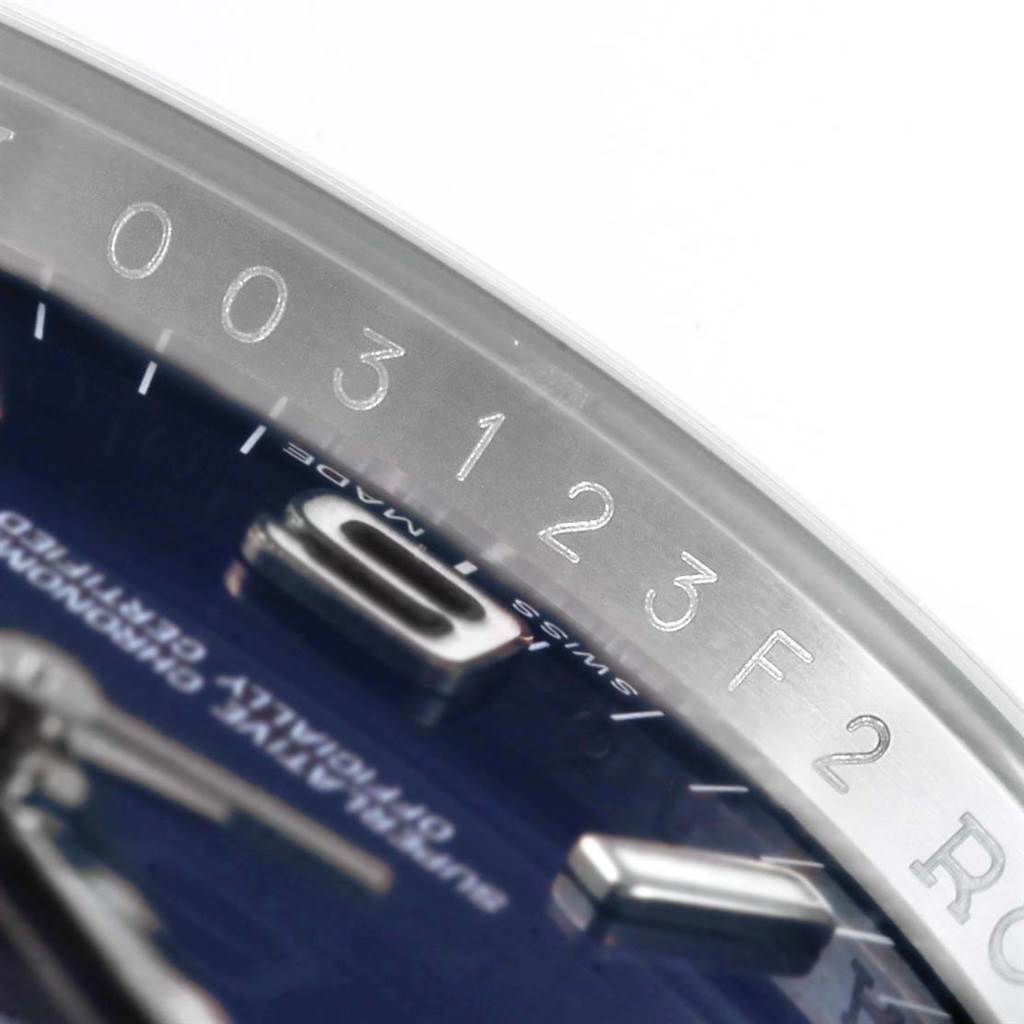 Close-up of the Rolex Oyster Perpetual 116000 Men's Stainless Steel Blue Dial 116000 Men's Stainless Steel Blue Dial model, showing the edge of the dial, part of an hour marker, and the inner bezel with engravings.