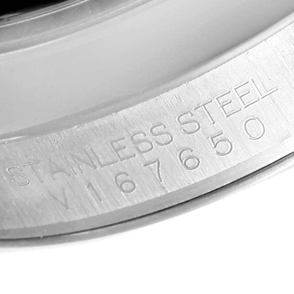 The image shows a close-up of the Rolex Oyster Perpetual 116000 Men's Stainless Steel Black Dial 116000 Men's Stainless Steel Black Dial's inner bezel with "STAINLESS STEEL" and a reference number inscribed.