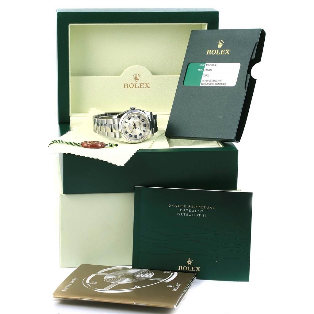 The image shows the Rolex Oyster Perpetual 116200 Men's Stainless Steel Silver Dial 116200 Men's Stainless Steel Silver Dial watch at an angle, with its box, warranty card, manuals, and a cleaning cloth.