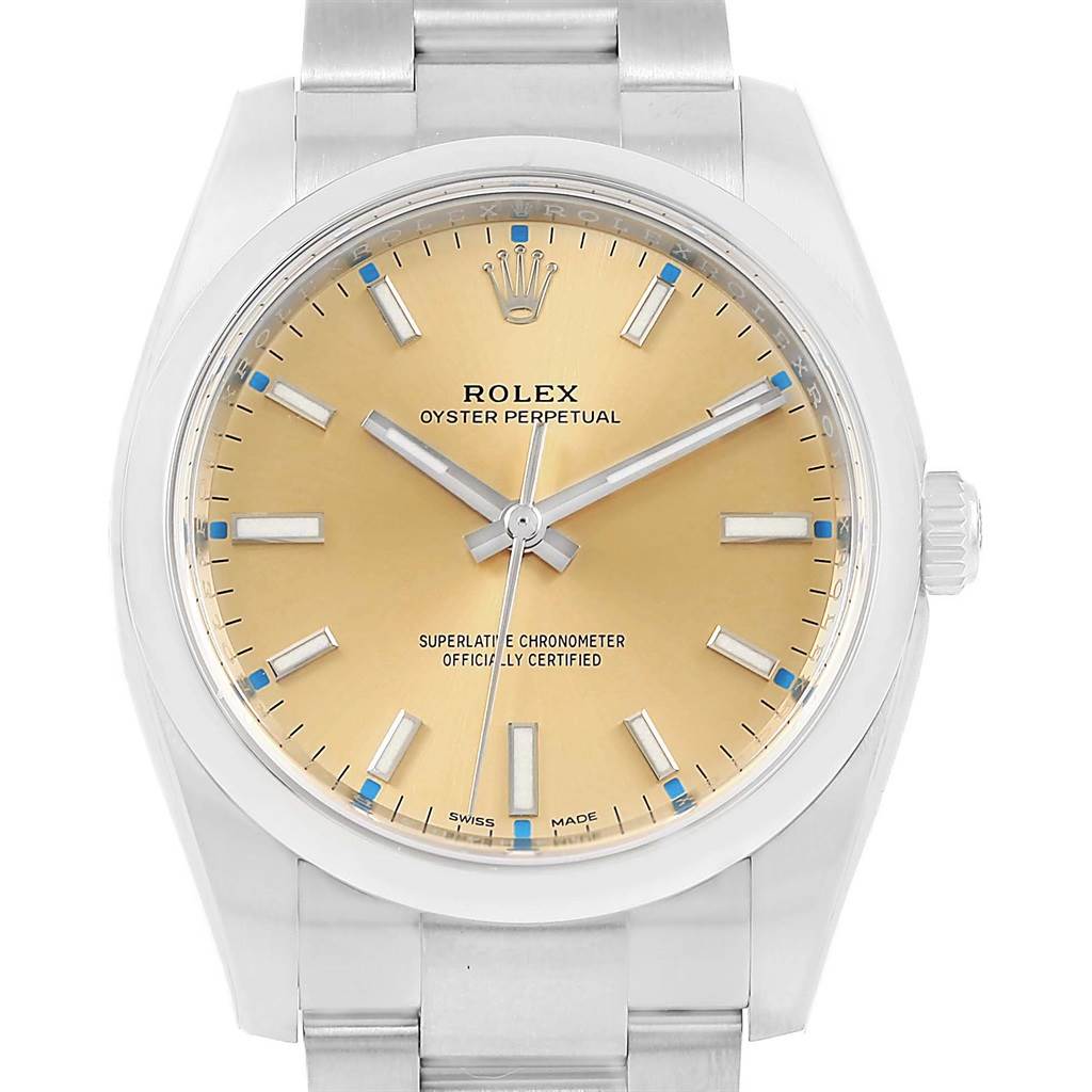 The image shows a frontal view of a Rolex Oyster Perpetual 114200 Stainless Steel Champagne Dial 114200 Stainless Steel Champagne Dial watch, highlighting its bezel, dial, hands, and bracelet.