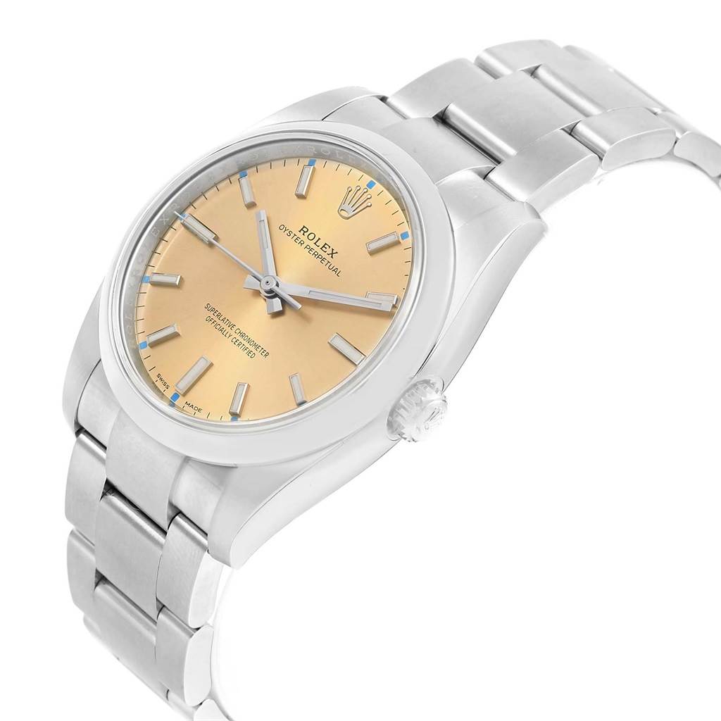 The image showcases a Rolex Oyster Perpetual 114200 Stainless Steel Champagne Dial 114200 Stainless Steel Champagne Dial watch at an angled top-down view, highlighting its face, crown, and bracelet.