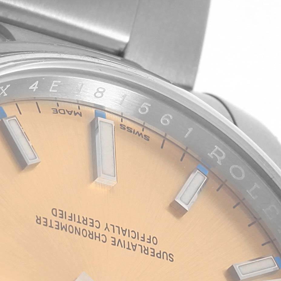 The image shows the dial, bezel, and part of the bracelet clasp of the Rolex Oyster Perpetual 114200 Stainless Steel Champagne Dial 114200 Stainless Steel Champagne Dial watch at a close-up angle.