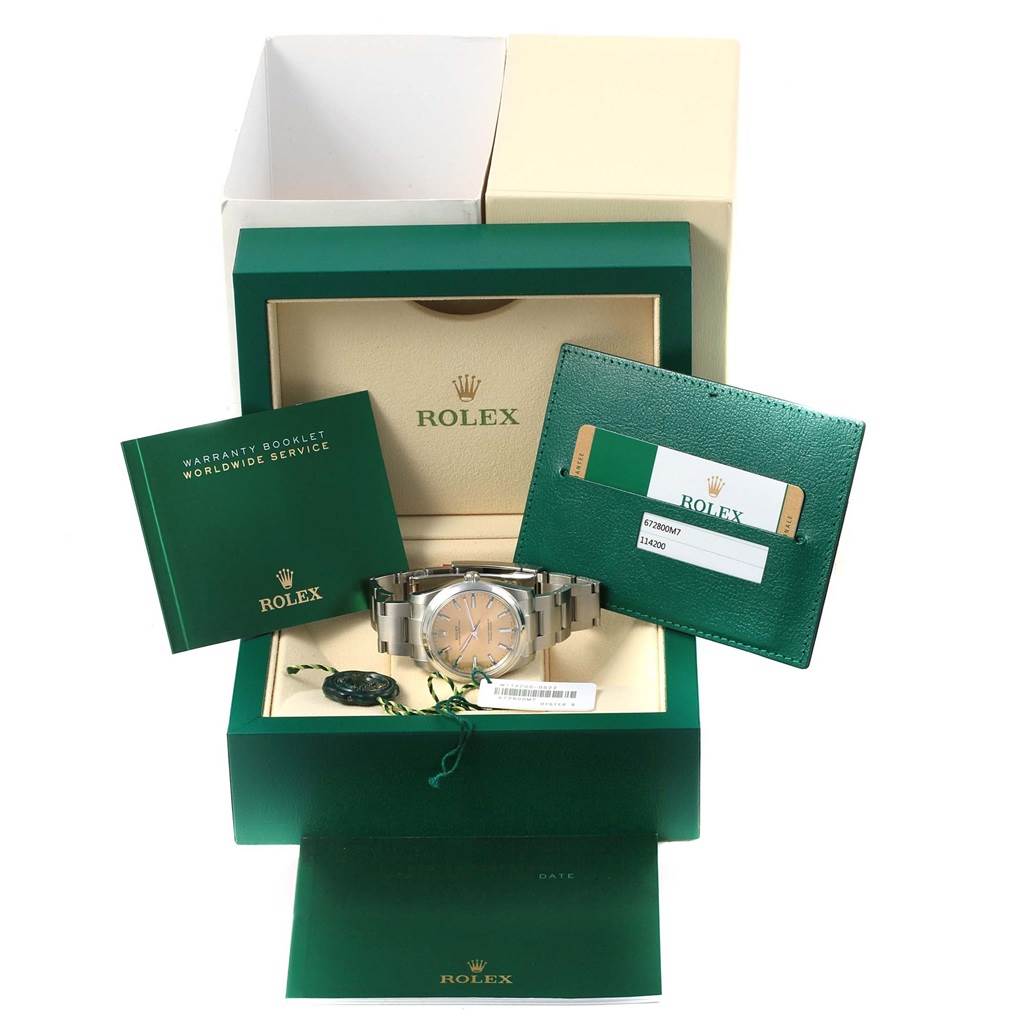 The image shows a Rolex Oyster Perpetual 116000 Stainless Steel Champagne Dial 116000 Stainless Steel Champagne Dial watch with its box, warranty booklet, service manual, and warranty card.
