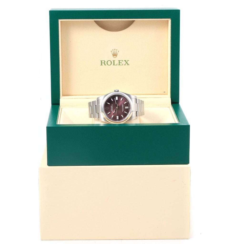 This image shows a Rolex Oyster Perpetual 116000 Stainless Steel Burgundy Dial 116000 Stainless Steel Burgundy Dial watch displayed face-up in an open green watch box.
