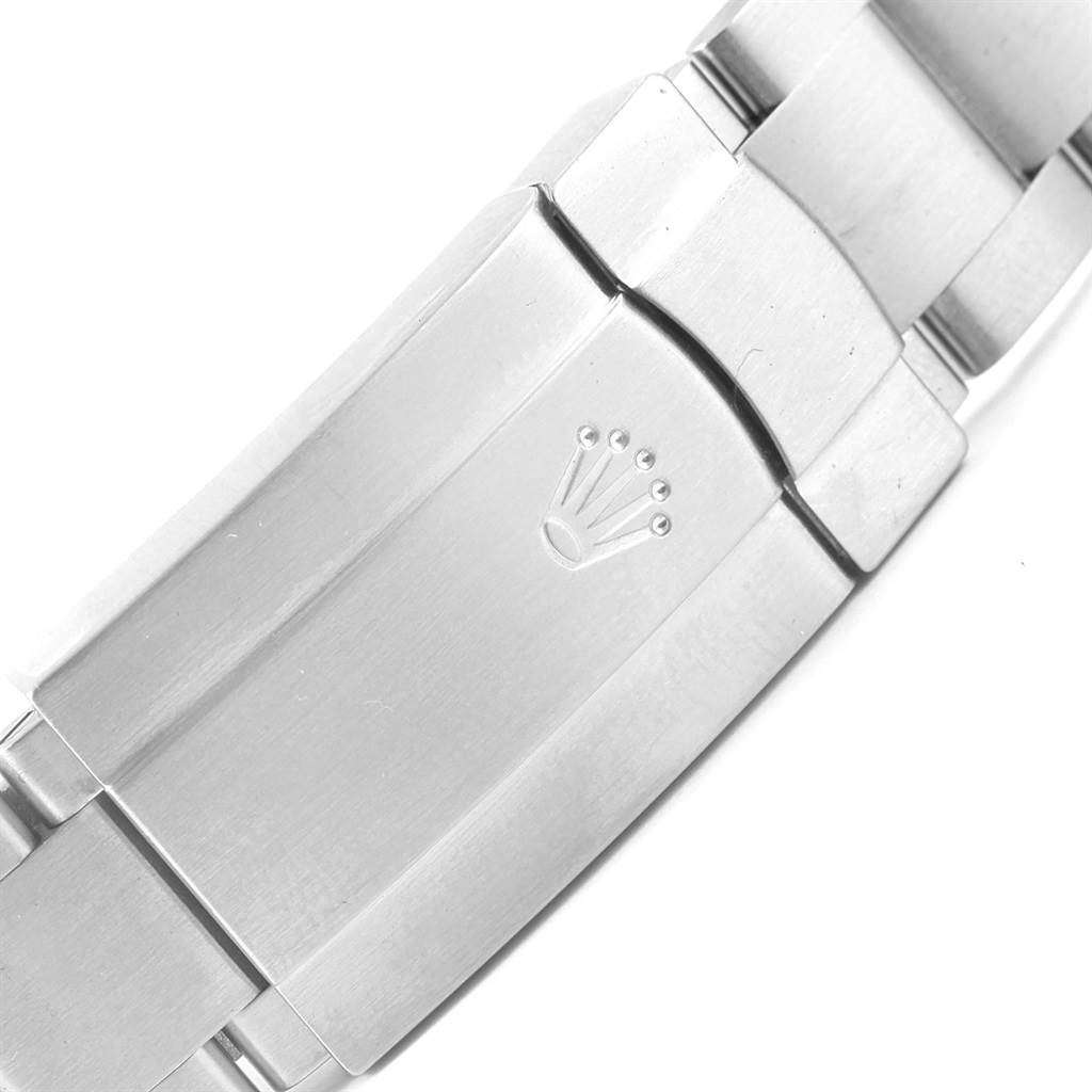 The image shows the clasp of a Rolex Oyster Perpetual 116000 Stainless Steel Burgundy Dial 116000 Stainless Steel Burgundy Dial watch from a close-up angle, featuring the Rolex logo.