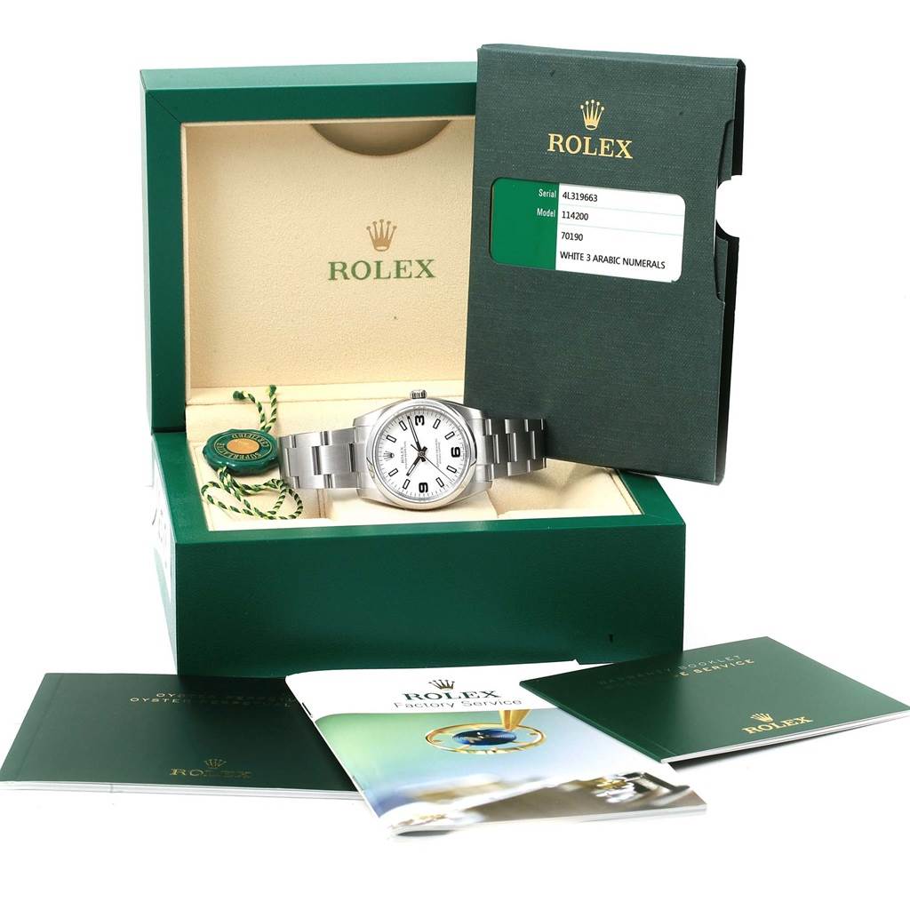The Rolex Oyster Perpetual 114200 Stainless Steel White Dial 114200 Stainless Steel White Dial watch is shown in its box along with accompanying booklets and a certification tag.