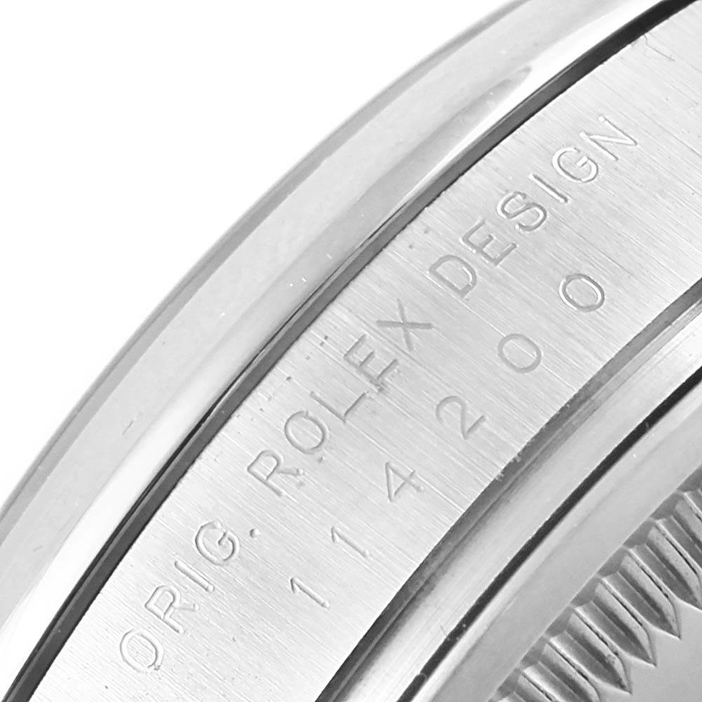 This close-up image shows the engraved side of the bezel of a Rolex Oyster Perpetual 114200 Stainless Steel White Dial 114200 Stainless Steel White Dial watch.