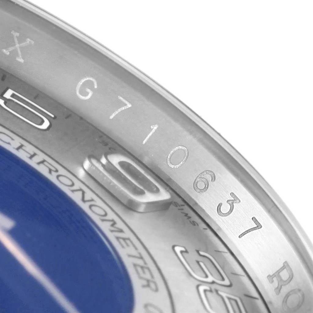 This image shows a close-up angle of the Rolex Oyster Perpetual 116000 Men's Stainless Steel Silver Dial 116000 Men's Stainless Steel Silver Dial watch, focusing on the bezel, part of the dial, and engraved numbers.