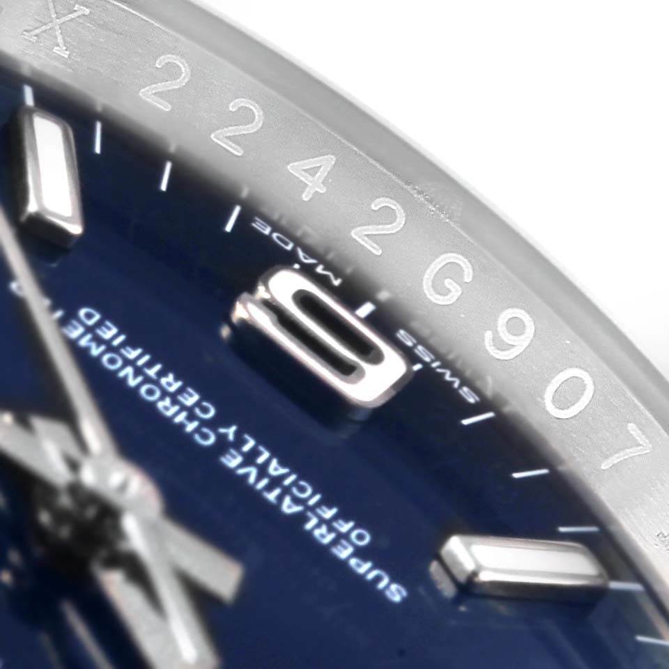 The image shows a close-up of the dial and part of the bezel of a Rolex Oyster Perpetual 116000 Men's Stainless Steel Blue Dial 116000 Men's Stainless Steel Blue Dial watch.