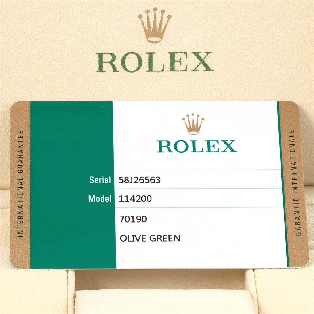The image shows the international guarantee card for the Rolex Oyster Perpetual 114200 Stainless Steel Green Dial 114200 Stainless Steel Green Dial model 114200 in olive green.