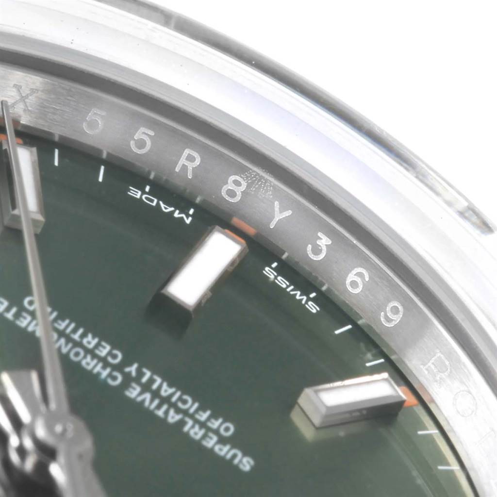 This close-up angle of the Rolex Oyster Perpetual 114200 Green Dial 114200 Green Dial watch shows parts of the dial, hour markers, and text indicating "Swiss Made."