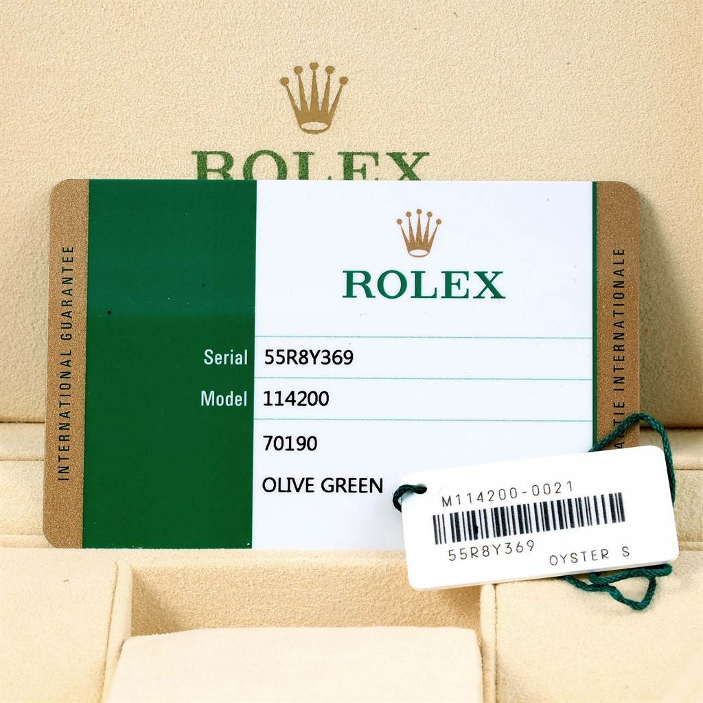This image shows the warranty card and tag for the Rolex Oyster Perpetual 114200 Green Dial 114200 Green Dial model 114200.