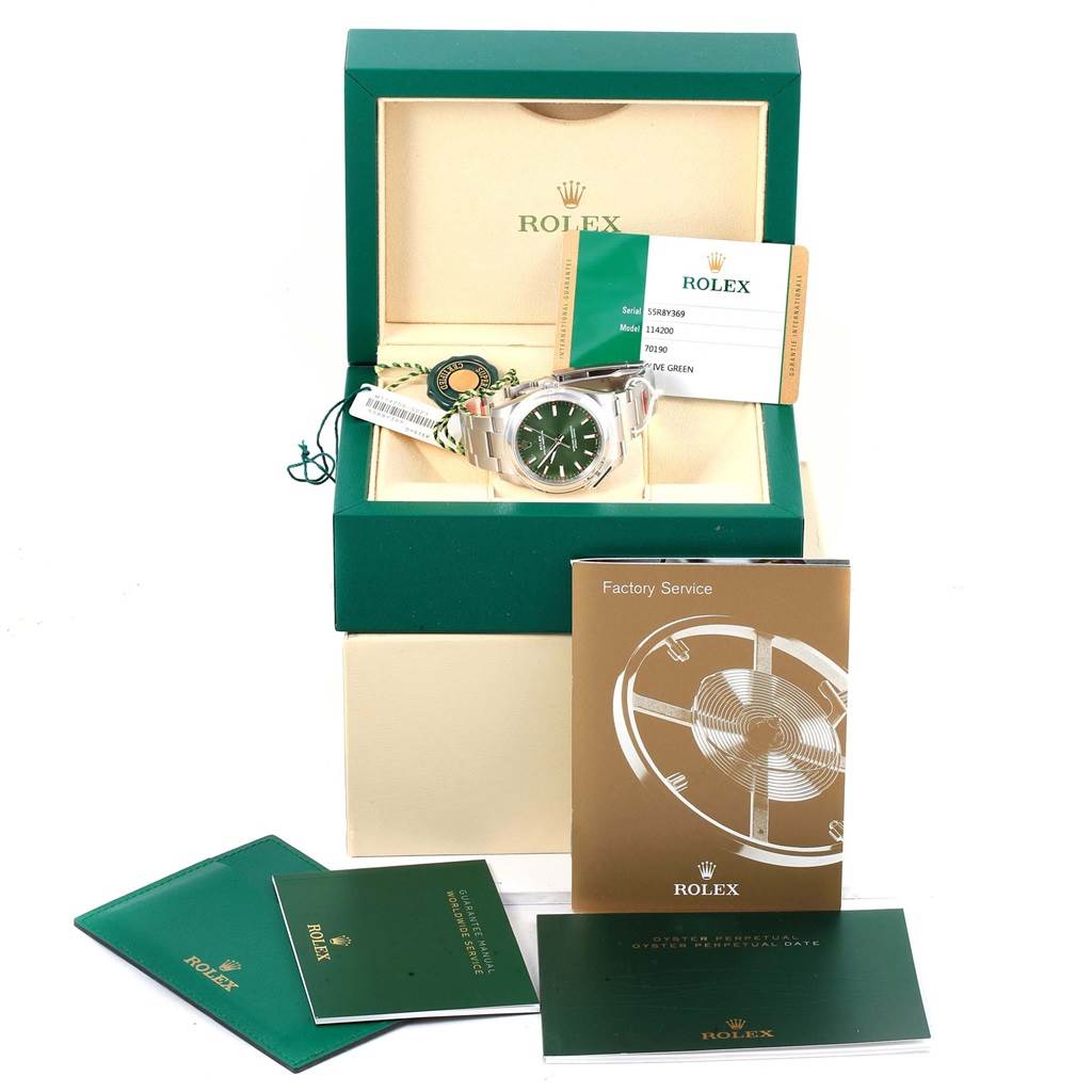 The image shows a Rolex Oyster Perpetual 114200 Green Dial 114200 Green Dial watch, displayed in its box with accompanying documents, tags, and warranty card.