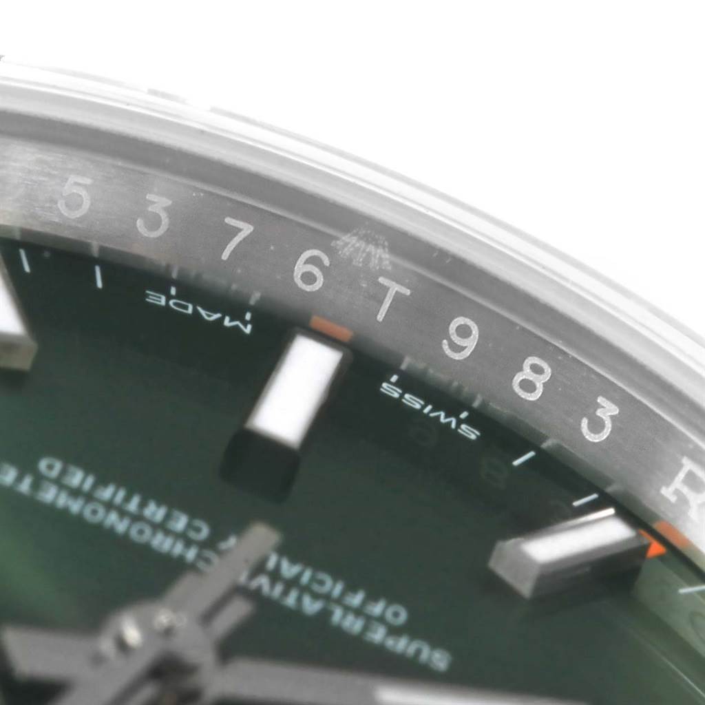 The image shows a close-up of the dial and edge of the bezel of the Rolex Oyster Perpetual 114200 Stainless Steel Green Dial 114200 Stainless Steel Green Dial watch.