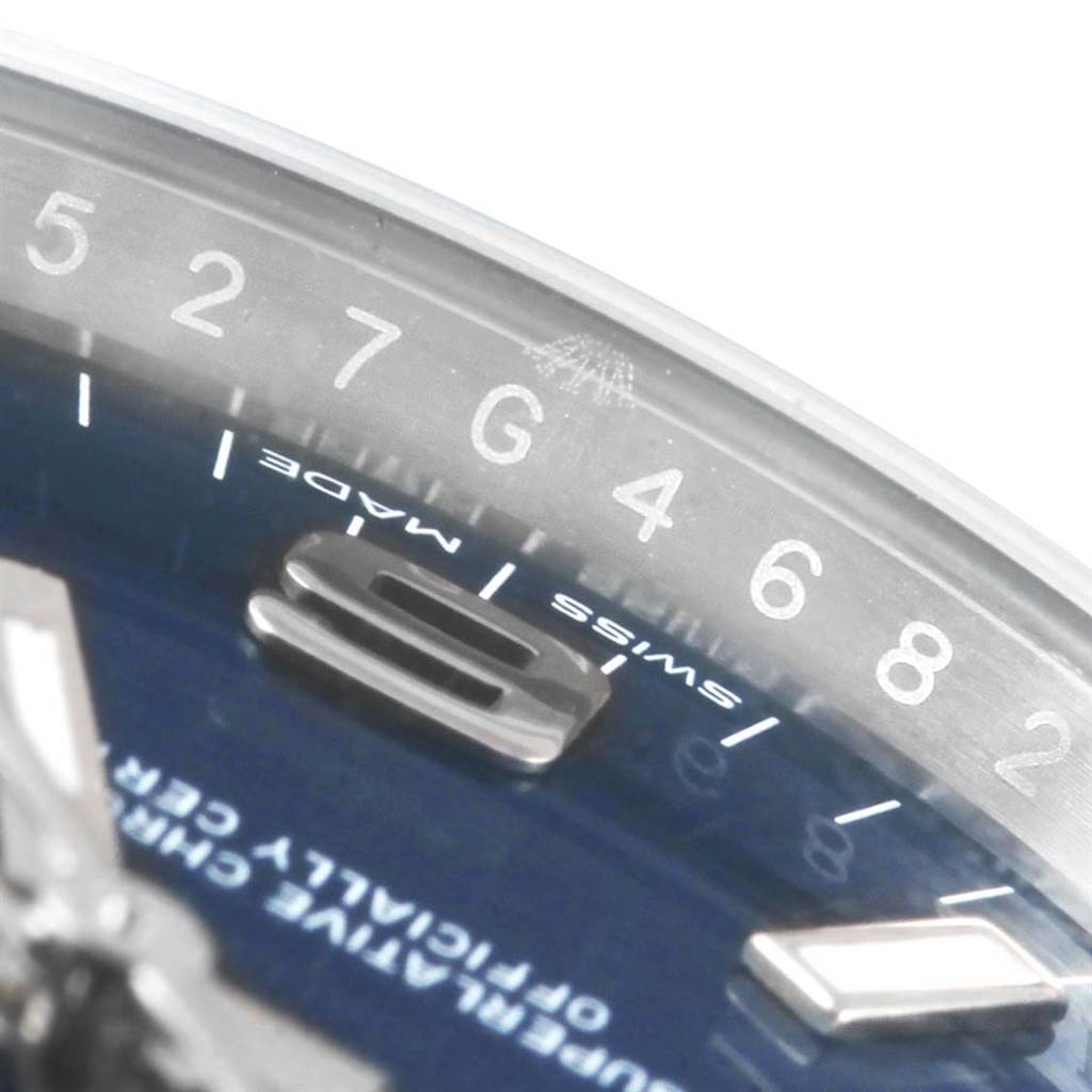 This close-up image of a Rolex Oyster Perpetual 114200 Men's Stainless Steel Blue Dial 114200 Men's Stainless Steel Blue Dial watch shows part of the dial and chapter ring with numerical and "Swiss Made" markings.