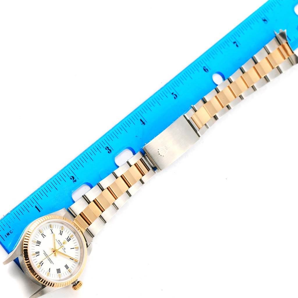 The image shows a Rolex Oyster Perpetual 14233 Men's Steel and Gold (two tone) White Dial 14233 Men's Steel and Gold (two tone) White Dial watch positioned next to a ruler, displaying its face, bezel, bracelet, and clasp.